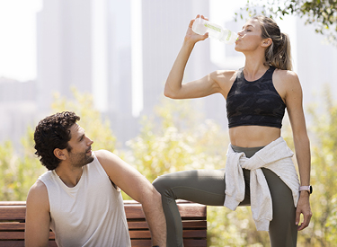 Couple drinking water in a urban park after workout