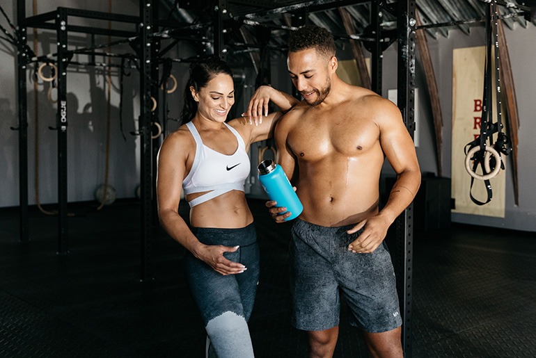 Man And Woman Looking At Water Bottle After Workout