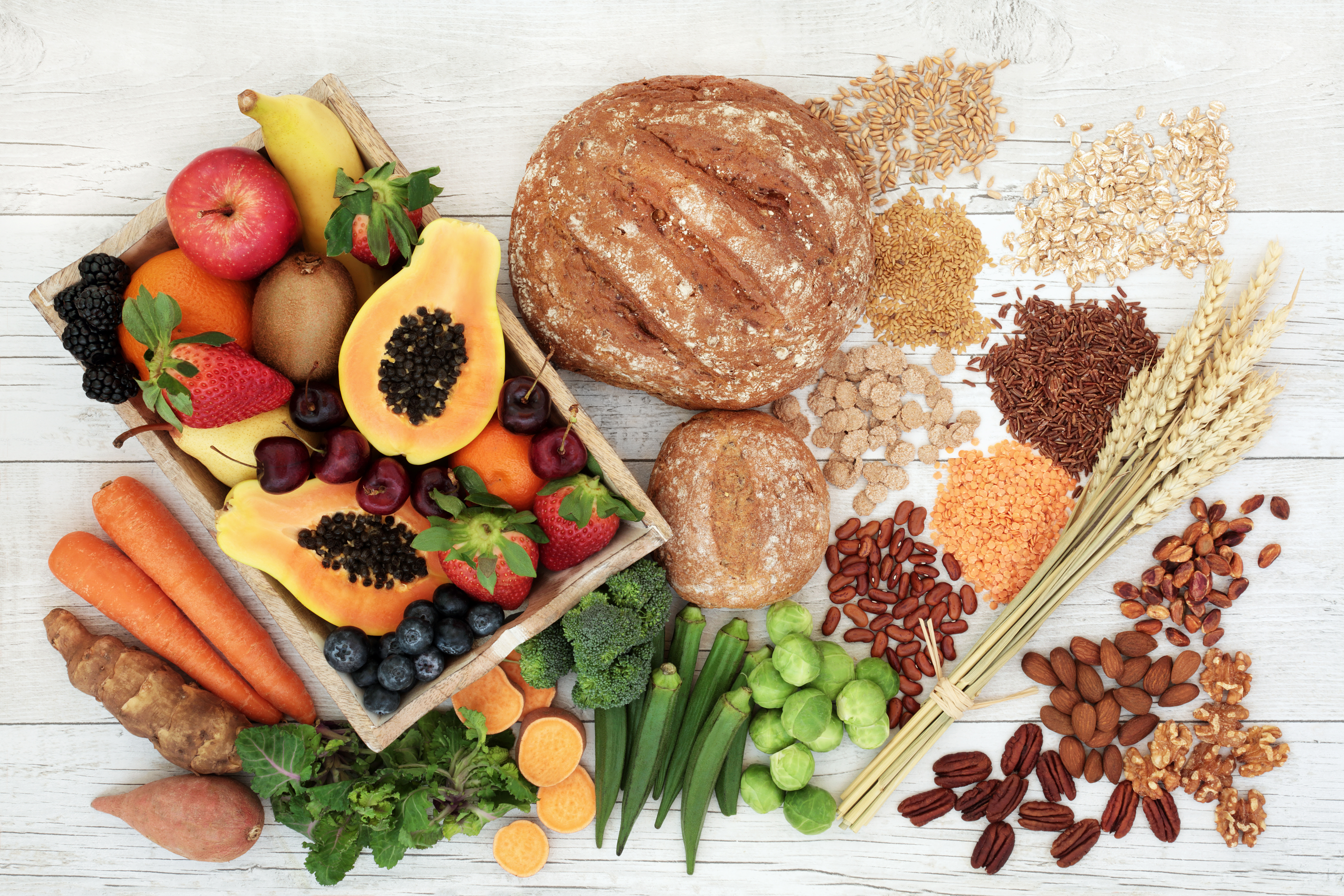 Healthy high fiber diet food concept with legumes, fruit, vegetables, wholegrain bread, cereals, grains, nuts and seeds. Super foods high in antioxidants, anthocyanins, omega 3 and vitamins. Rustic wood background, top view.