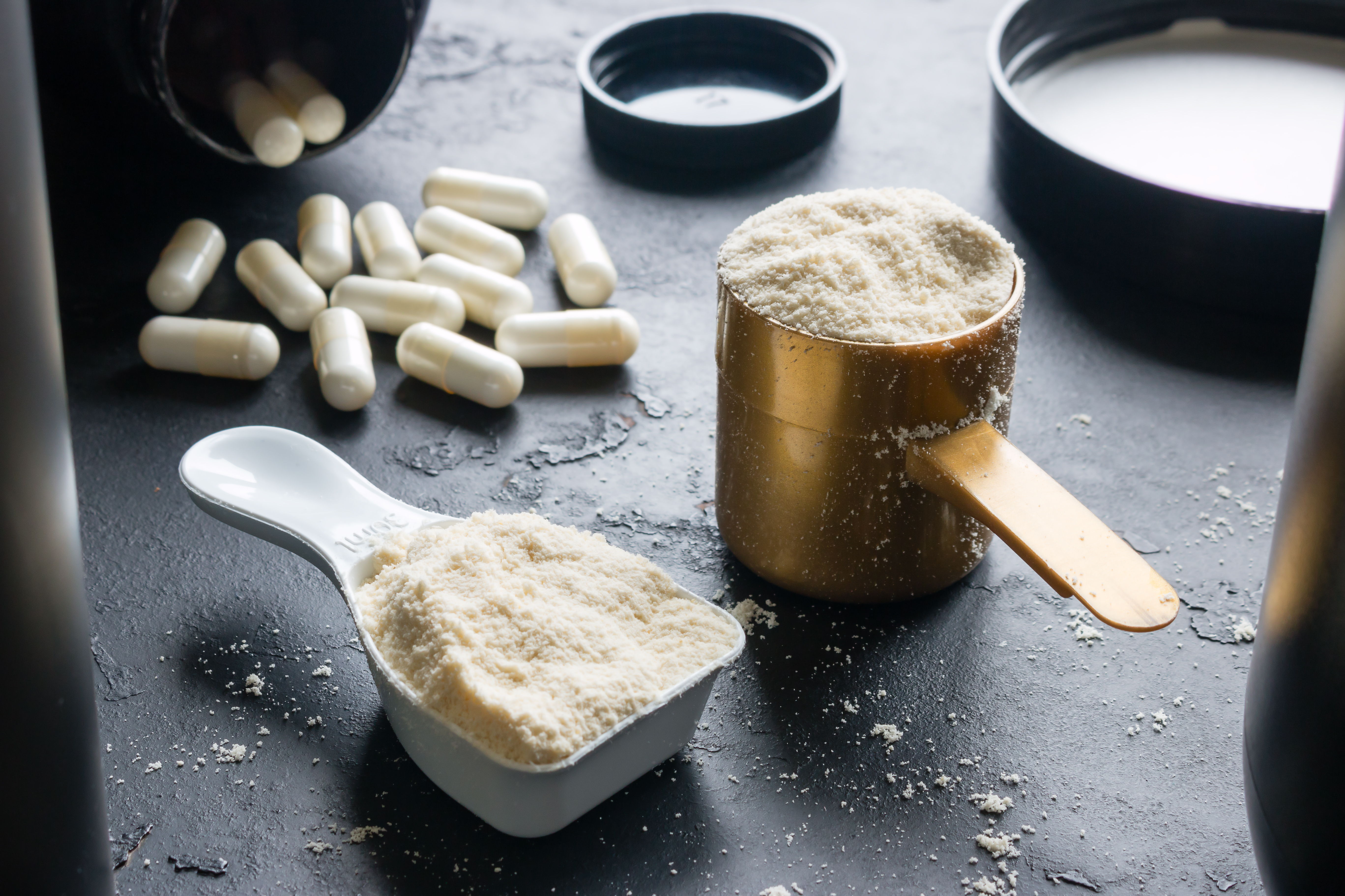 measuring spoons with sports supplements on a black background