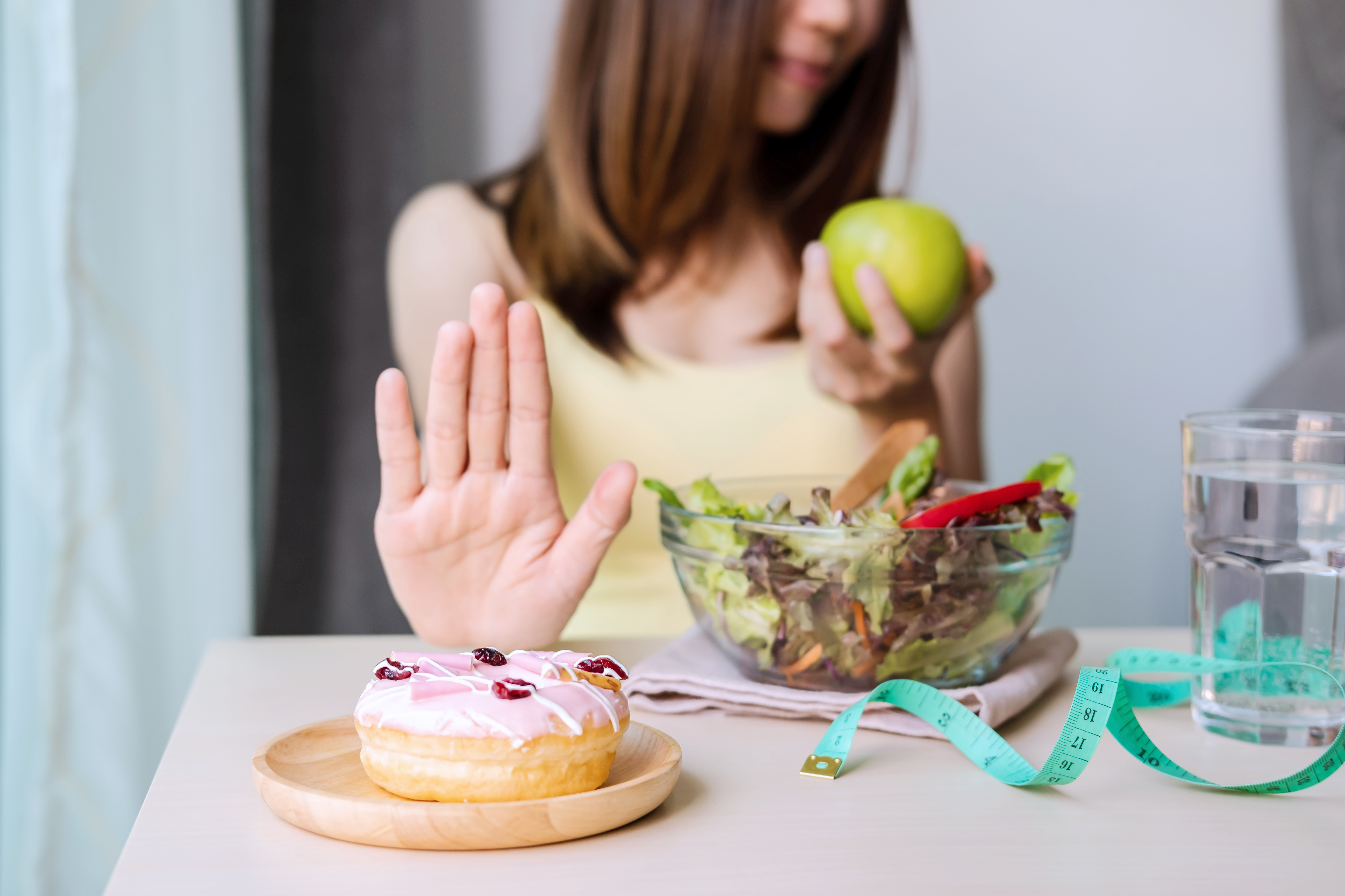 Young healthy woman using hand push out dessert and sweets and choose green apple and fresh salad, healthy lifestyle and diet concept