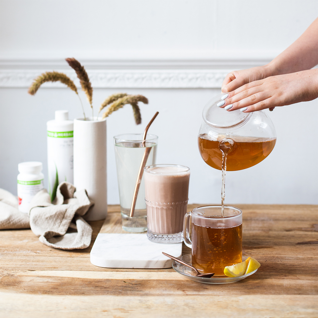 здравословна закуска herbalife nutrition и ръка, която налива лимонов чай в чаша