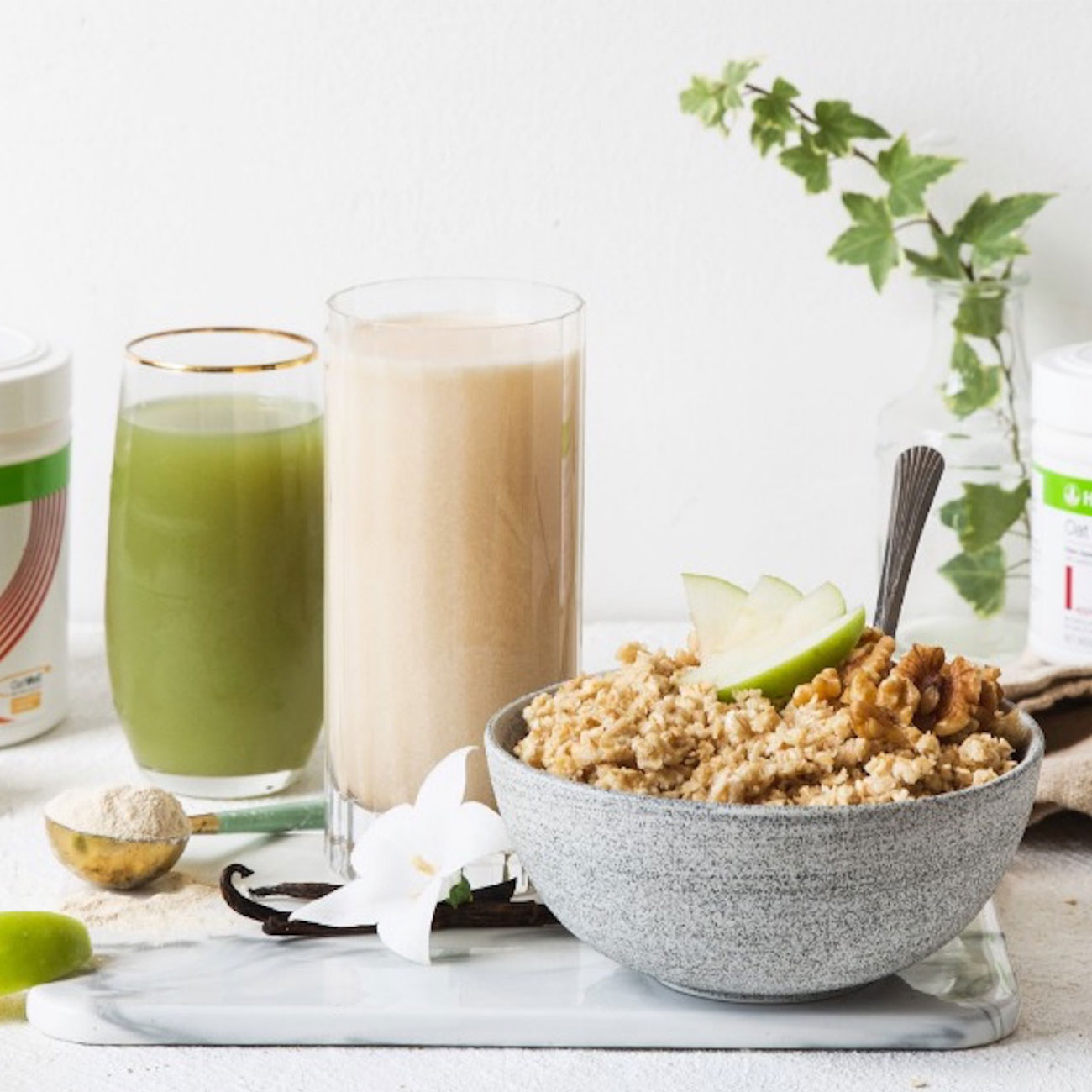 Schale mit Porridge, Apfelsaft und Herbalife Nutrition Shake auf einem Marmortisch