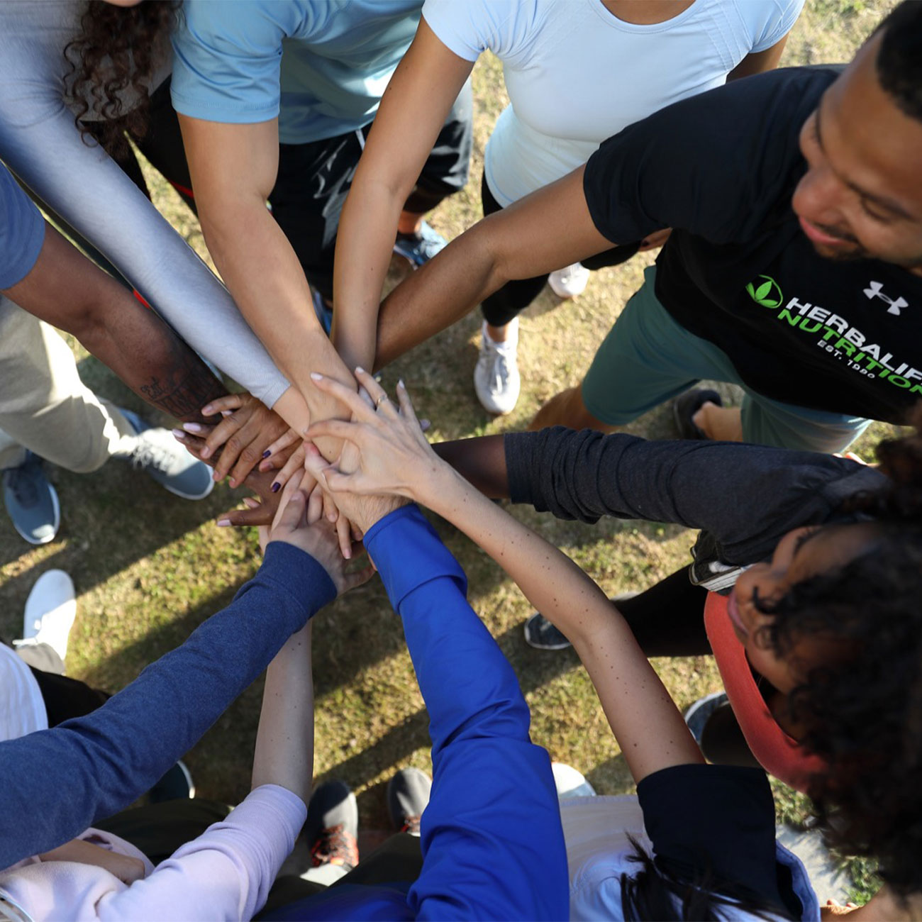 Group of Herbalife Nutrition members joining hands in a circle and smiling
