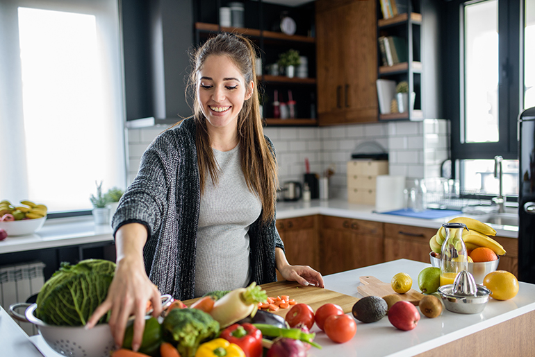 Eine schwangere Frau kocht eine gesunde Mahlzeit mit Gemüse.