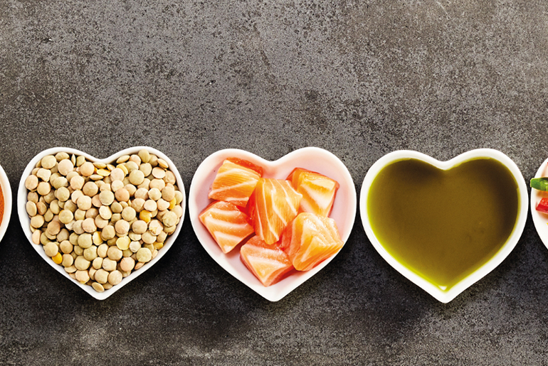 herzförmige schalen mit gesunden fetten wie lachs, linsen und olivenöl