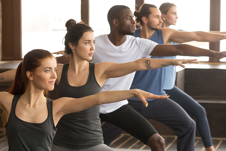 gruppe von frauen und m nnern strecken ihre arme aus w hrend sie yoga machen