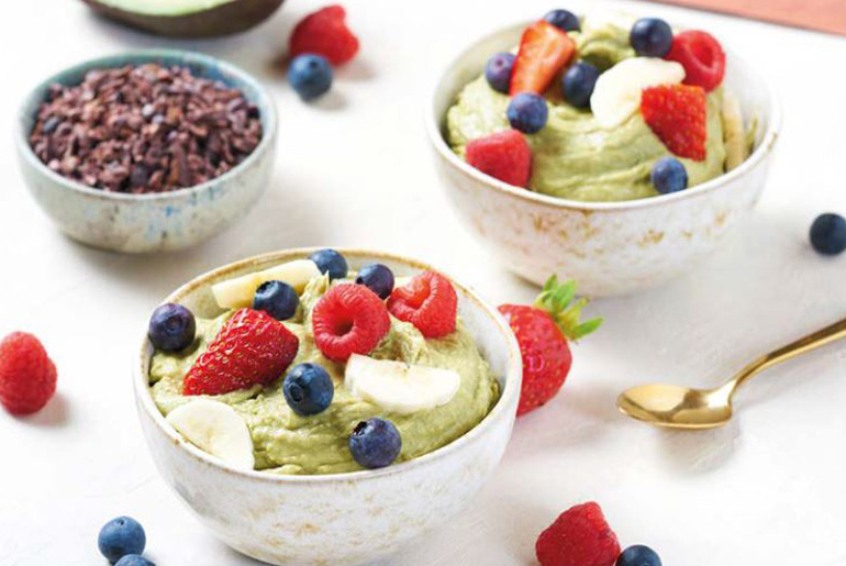 zwei schalen mit grüner eiscreme auf einem tisch mit einer anderen schale mit Schokoraspeln und einem goldenen löffel
