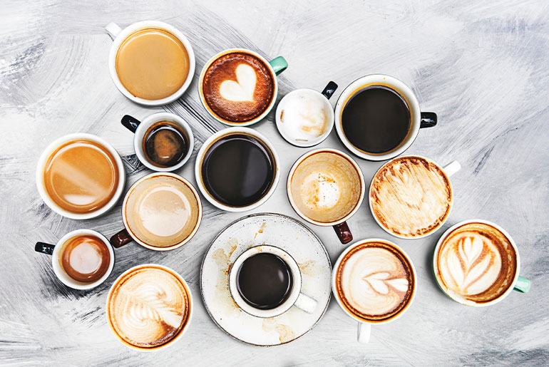 Overhead shot of various cups of coffee placed on a light grey plaster surface