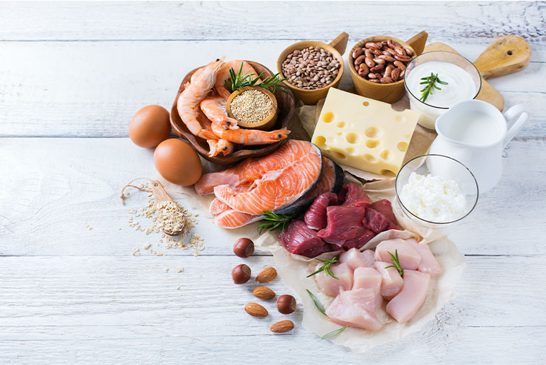 Overhead shot of high-protein foods placed on a white wood surface