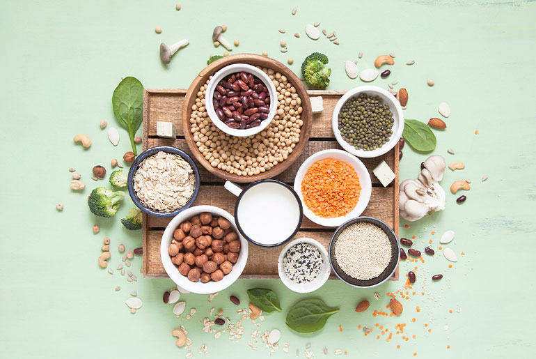 Overhead shot of high-protein nuts and legumes placed on a mint green surface