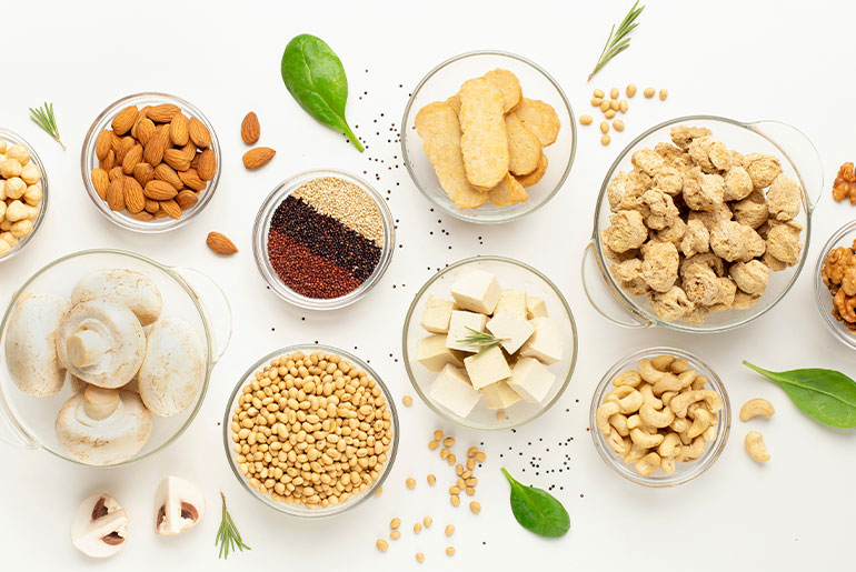 Overhead shot of different plant-based high-protein foods placed on a white surface