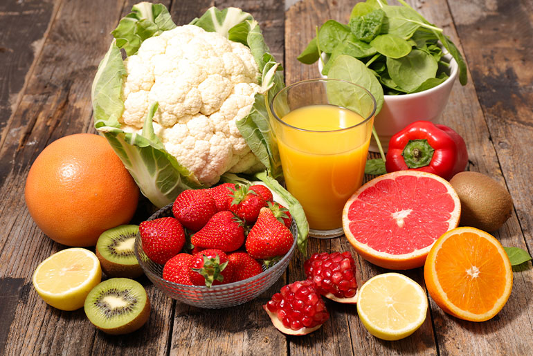 Angle shot of fruits and vegetables rich in Vitamin C placed on a dark wood surface