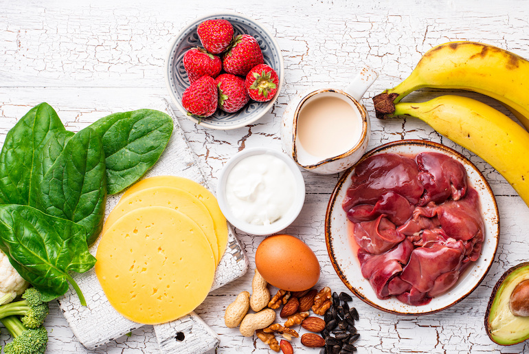Overhead shot of foods rich in B-vitamins placed on a white wood surface