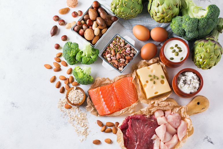 Overhead shot of high-protein foods placed on a light grey marble surface