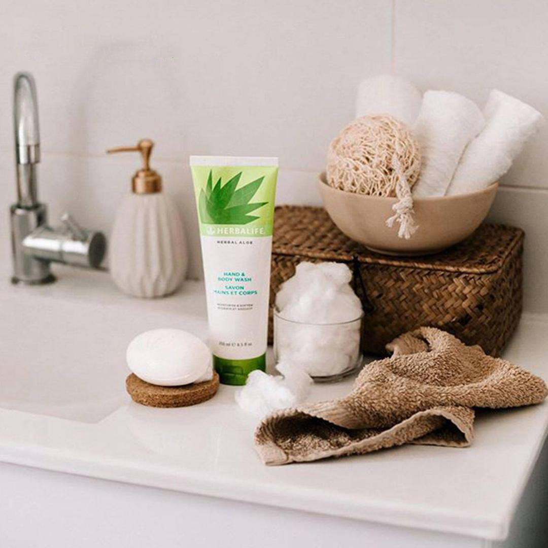 herbal aloe skin and hair products displayed on a sink with towels and bath essentials