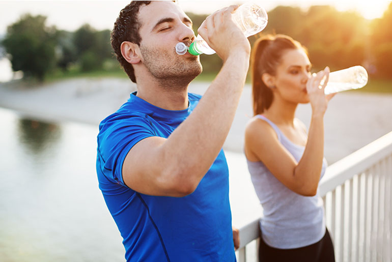 Two people drinking water to stay hydrated during workout