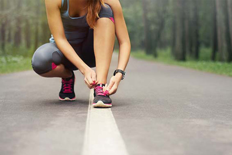 Woman tying her shoelaces during her outdoor run