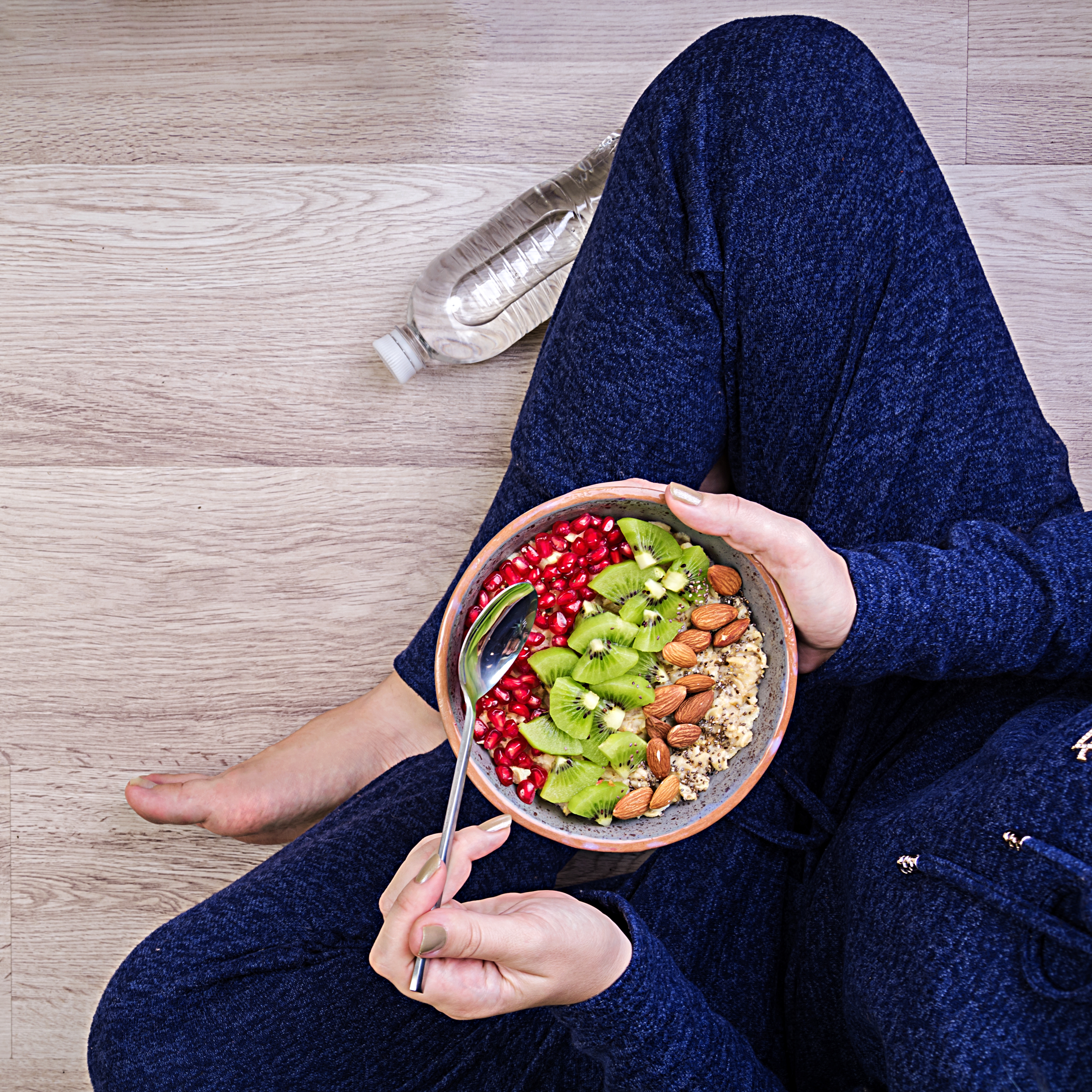 A nutrtional protein bowl with fruits and vegetable on the lap of the girl