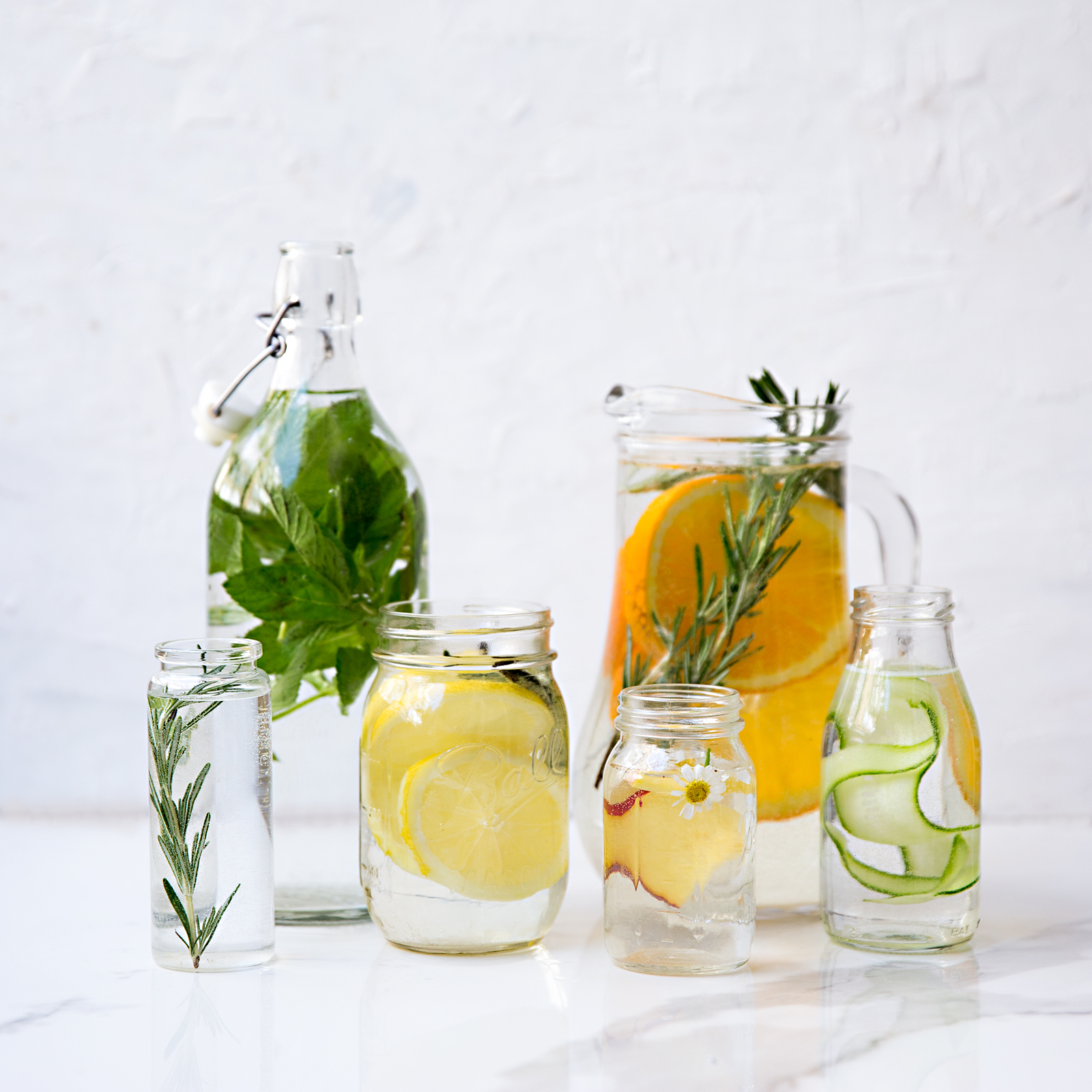 jugs and jars filled with water and aloe drink infused with fruit and herbs