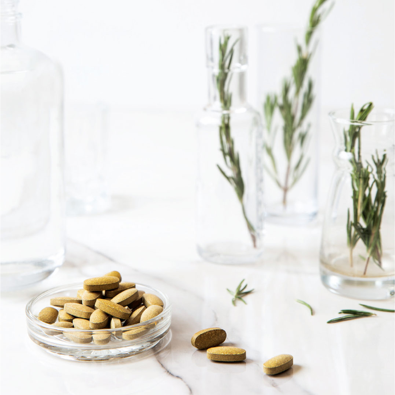 Herbalife Nutrition Roseguard tabletas en un tazón y hojas de romero