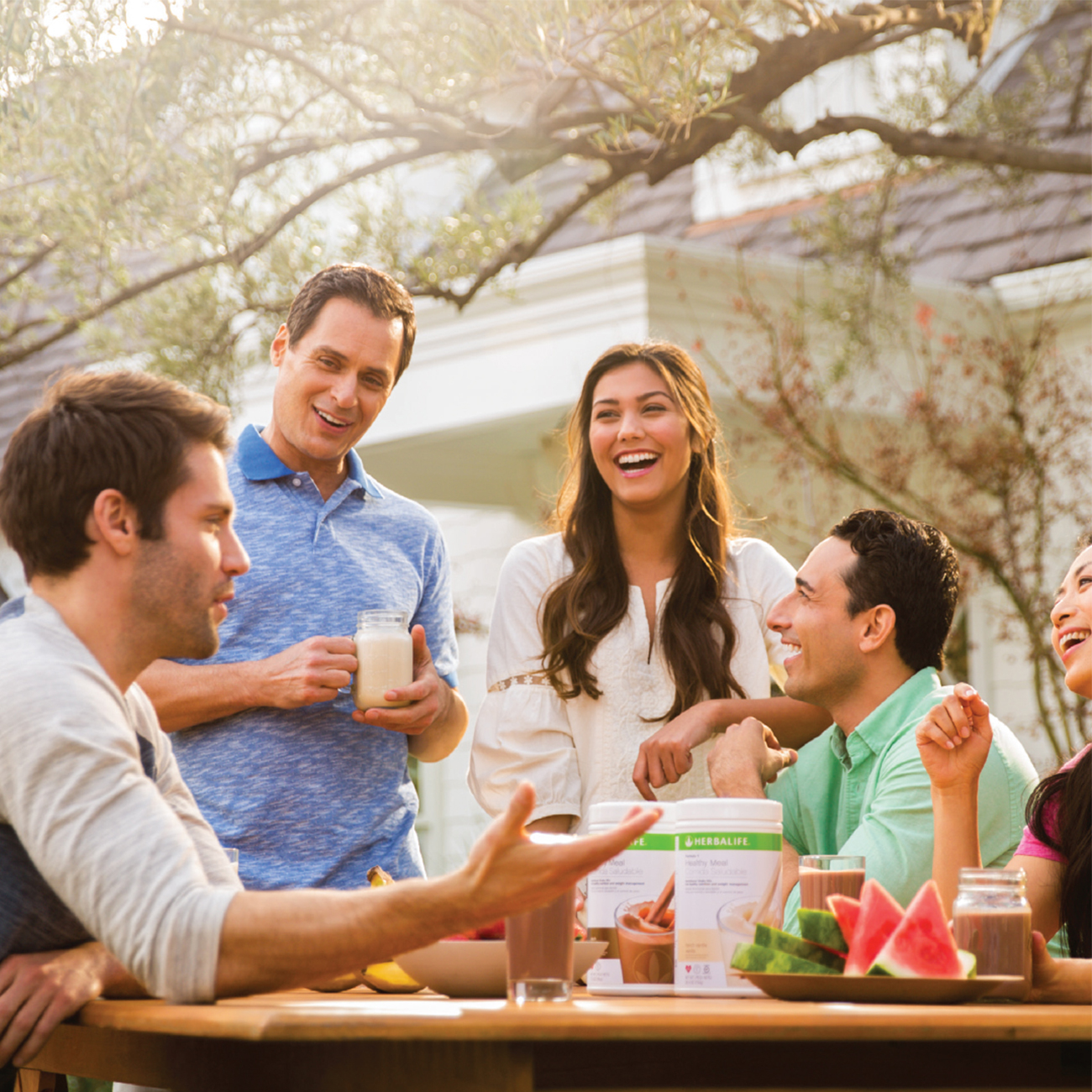 Un groupe d'amis s'est réuni dans un jardin et déguste des shakes Herbalife Nutrition