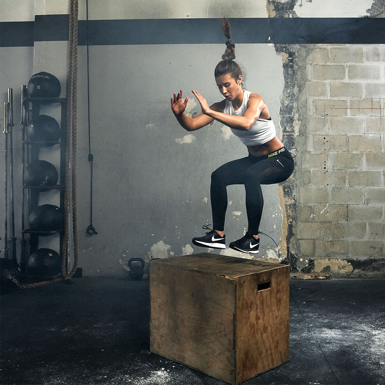 Спортистка скока на дрвена кросфит кутија за време на тренинг во фитнес клуб