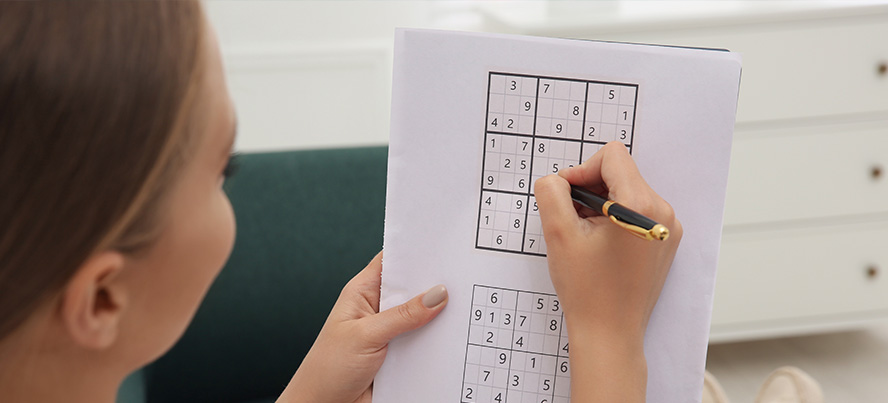 Mulher a exercitar o cérebro ao resolver um puzzle de sudoku