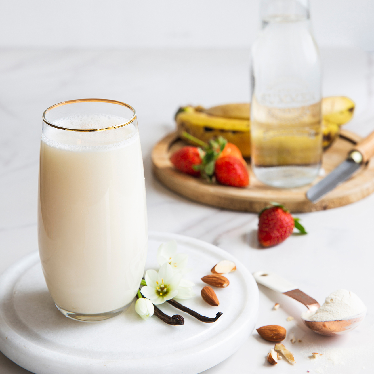 herbalife nutrition proteinski šejk u ukusu vanile u čaši sa svežim voćem i bademom.