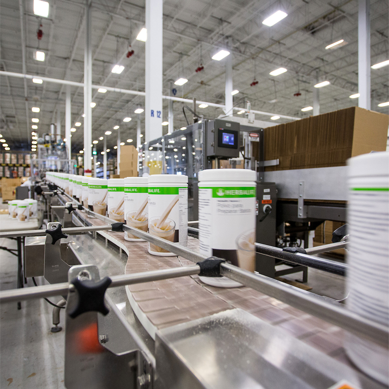 Image of herbalife nutrition factory with formula 1 canisters on the production belt